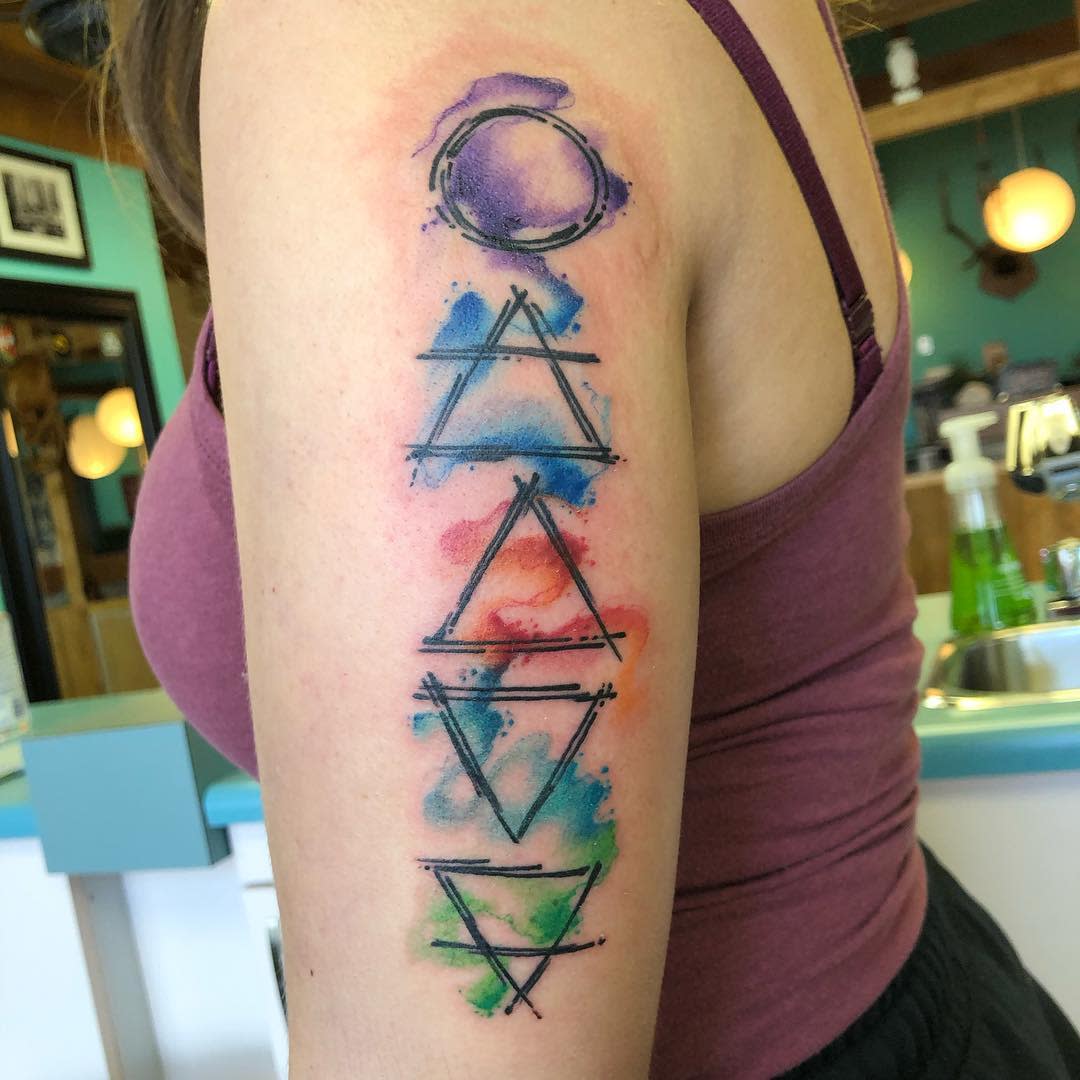 Tattoo of colorful geometric symbols representing four elements on the upper arm