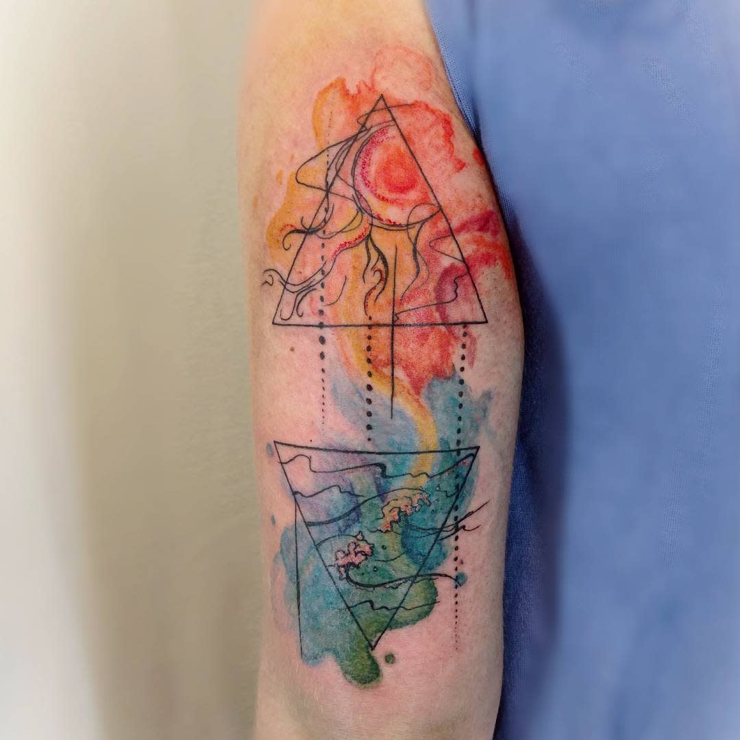 Colorful abstract tattoo featuring geometric shapes representing water and fire and watercolor effects on an arm