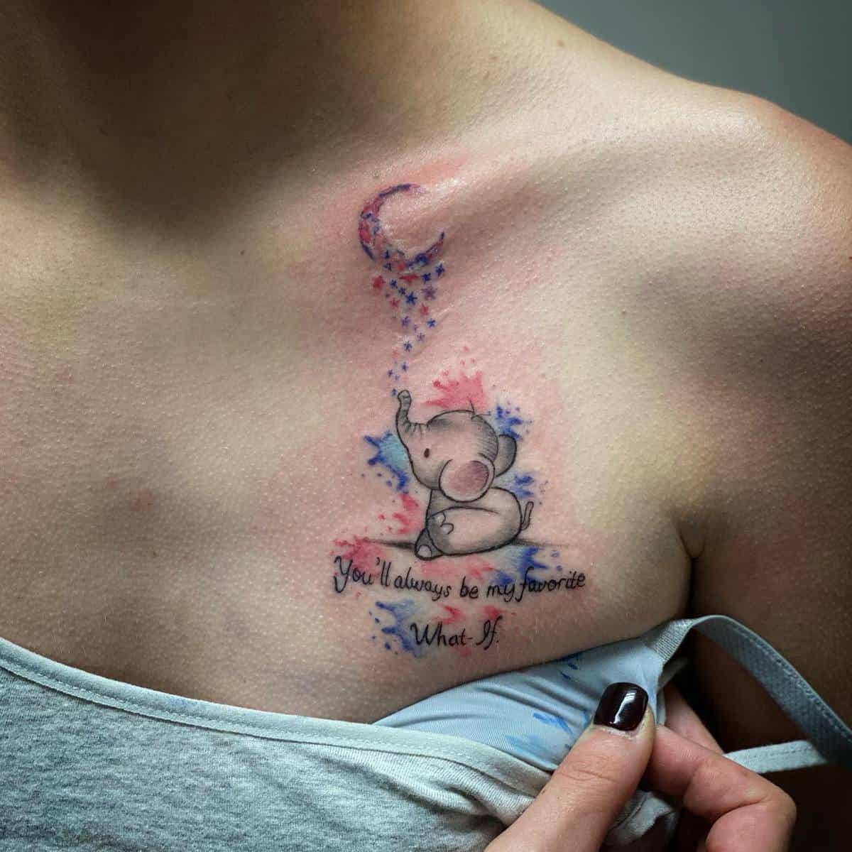 Tattoo of a cute elephant blowing colorful stars with the text "You'll always be my favorite What If" on someone's chest