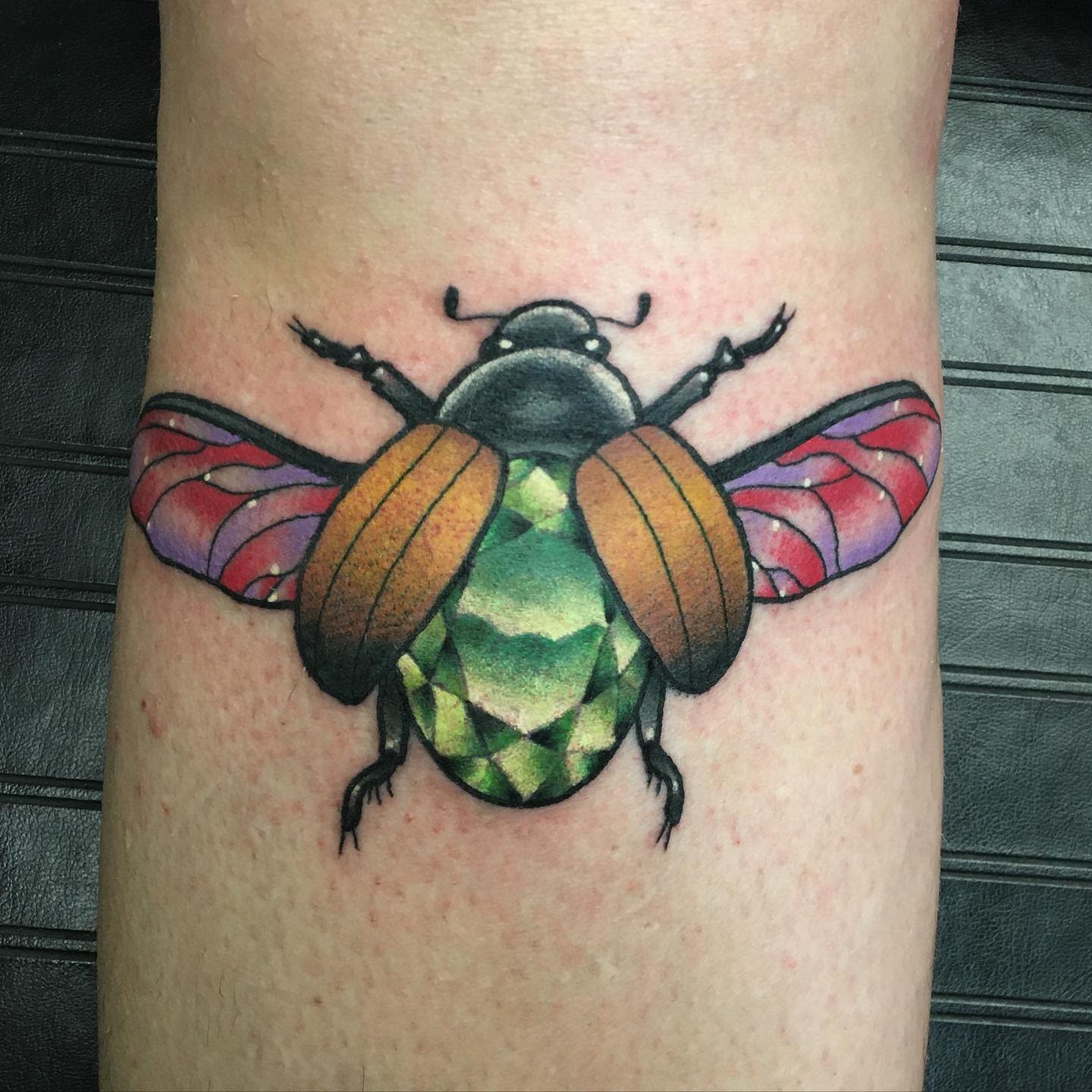 Colorful beetle tattoo with vibrant wings on skin