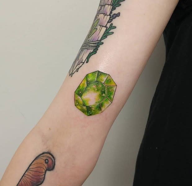 Forearm tattoo featuring an emerald