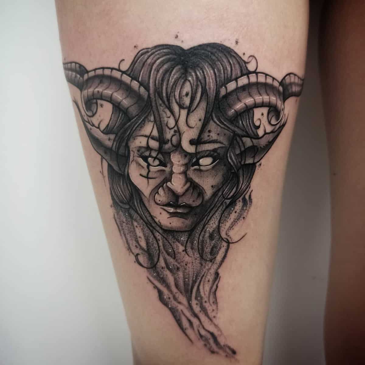 Tattoo of a demonic face with horns and long hair
