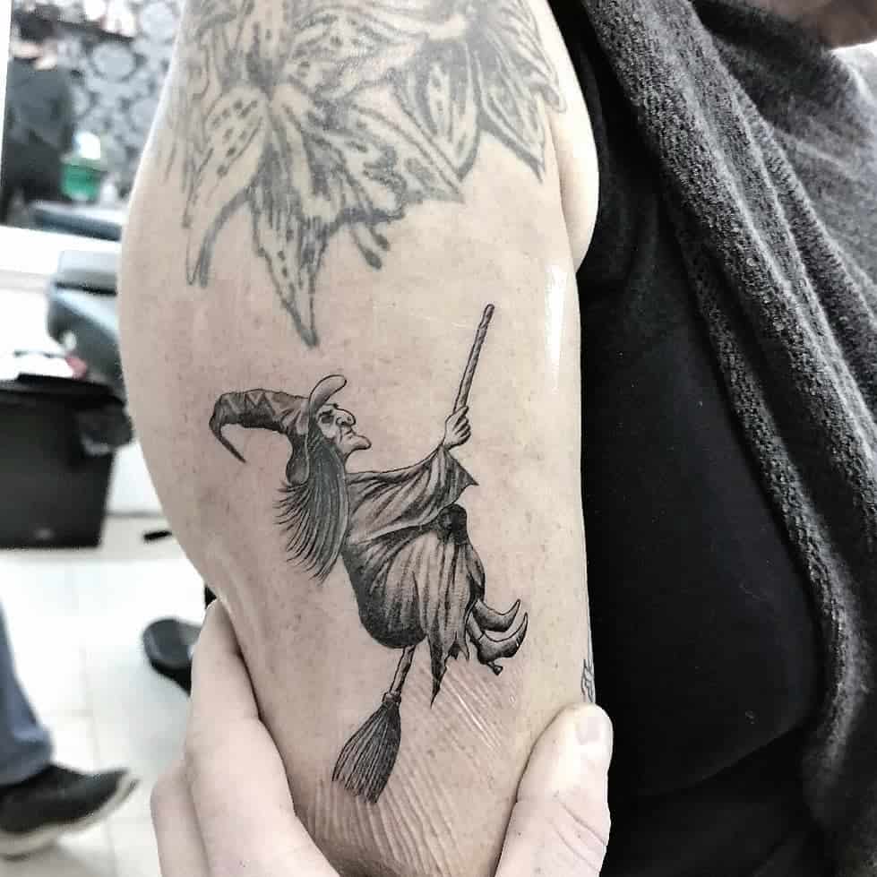 Tattoo of a witch flying on a broomstick on an upper arm