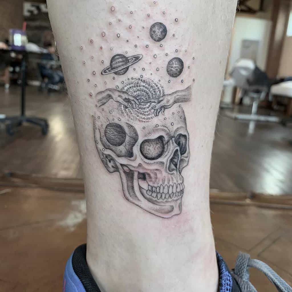 Tattoo of a skull with cosmic elements like planets and galaxies on a person's leg, intricately done with single needle precision