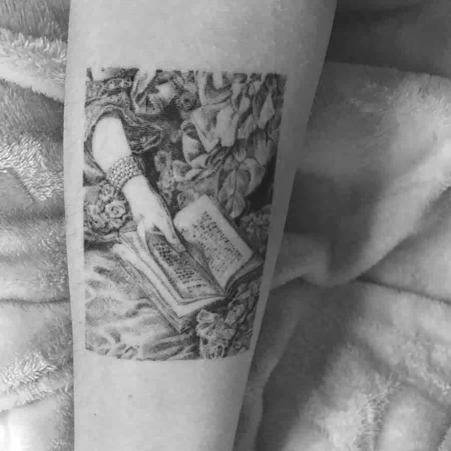 Black and grey tattoo of a hand holding an open book with floral patterns in the background, crafted using single needle technique