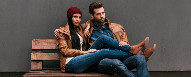 Fashionable couple sitting on bench in autumn