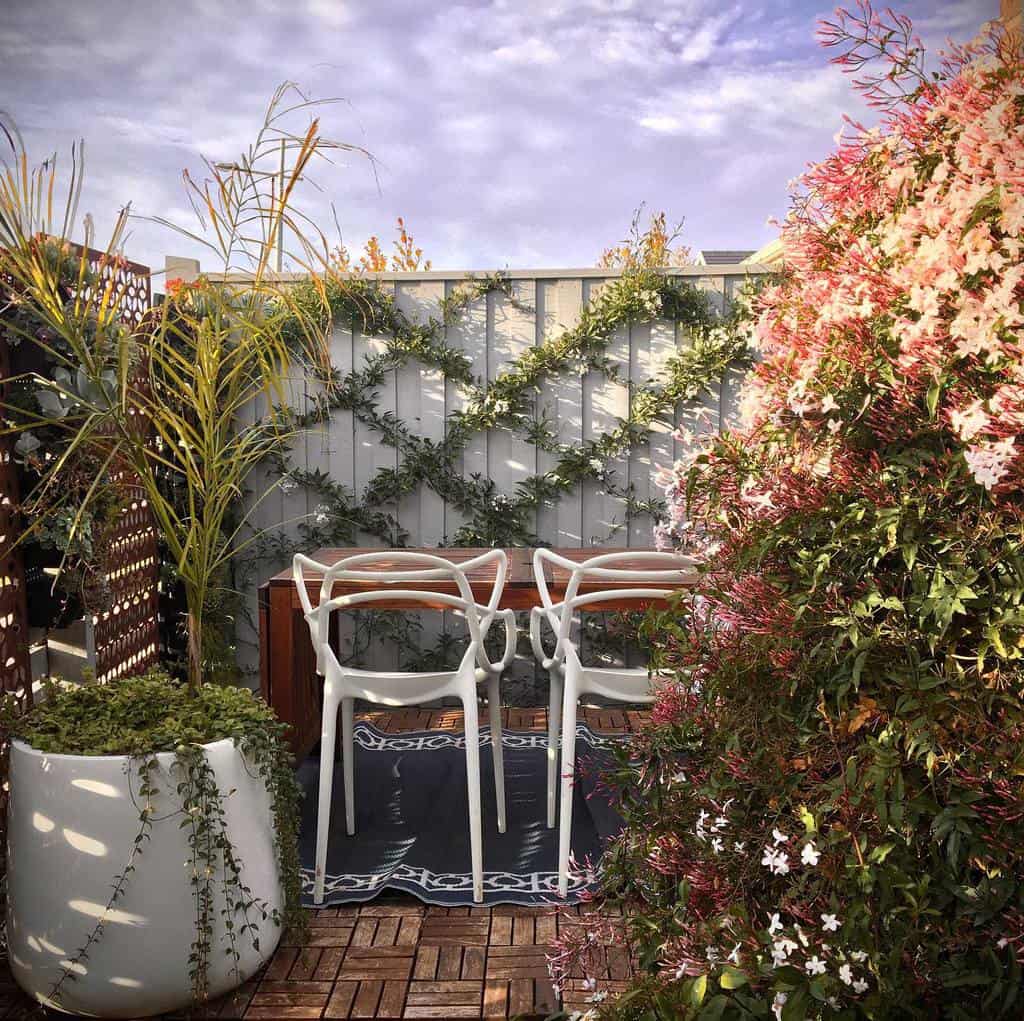 white chairs wood table lush garden