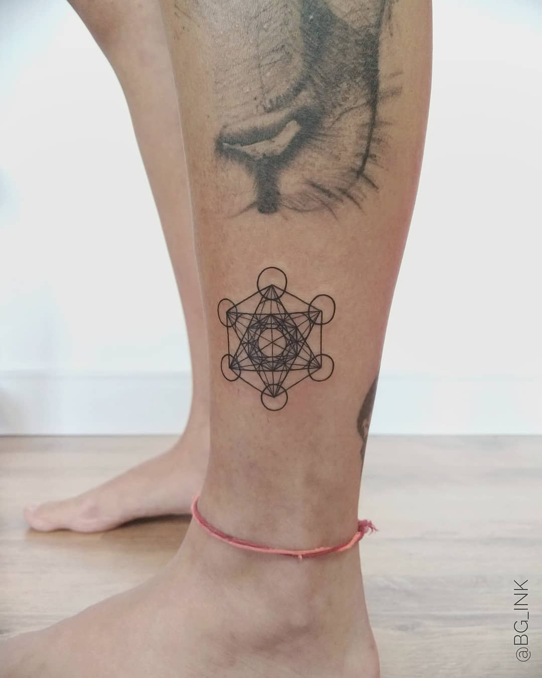 Geometric tattoo on back of leg above ankle, fine line ink