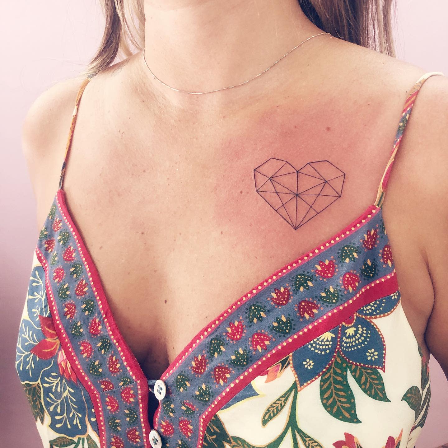 A geometric heart tattoo on the upper chest