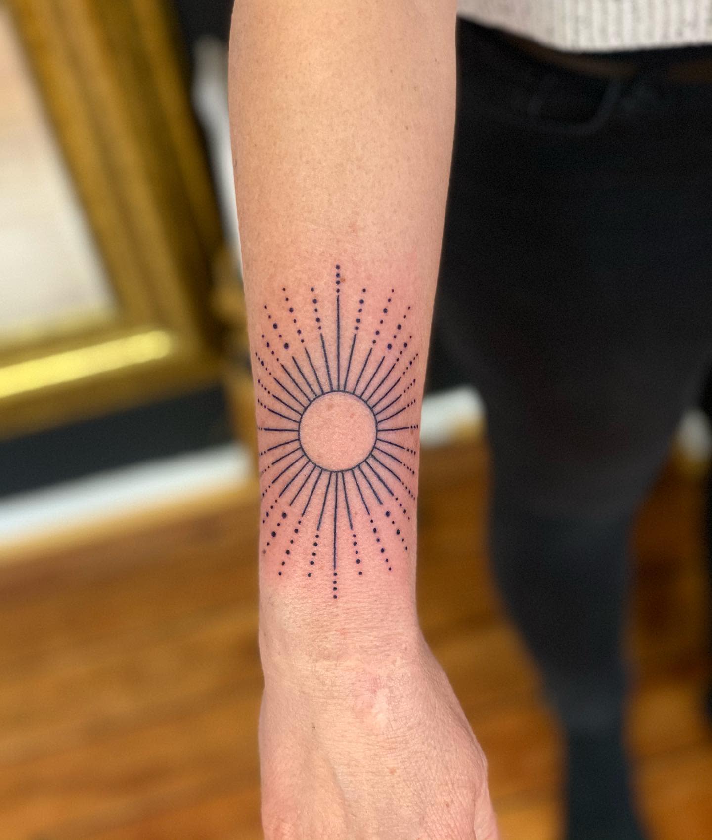 A sunburst design featuring minimalist radial lines and dots, centered around a circular shape