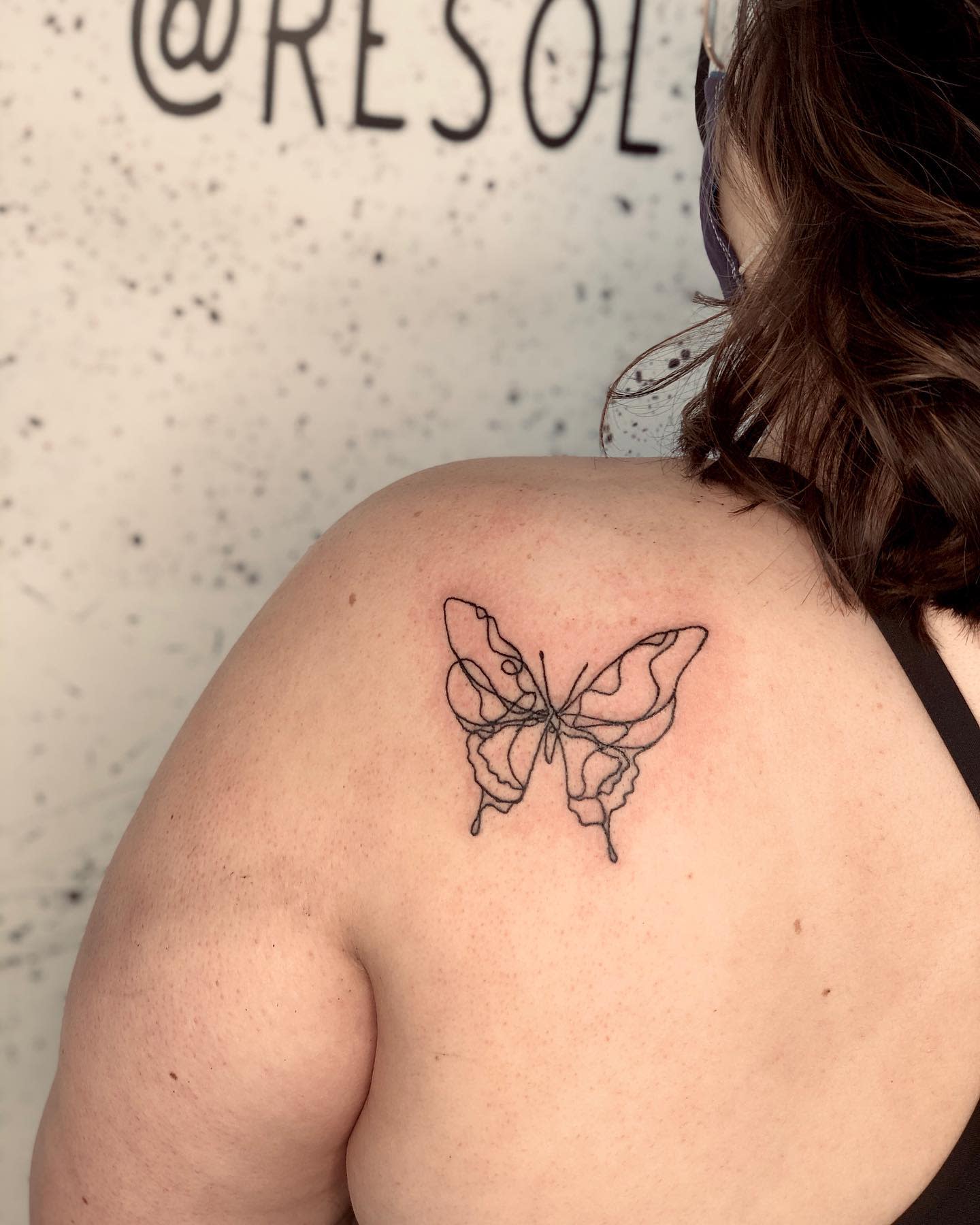A butterfly outline tattoo on the shoulder