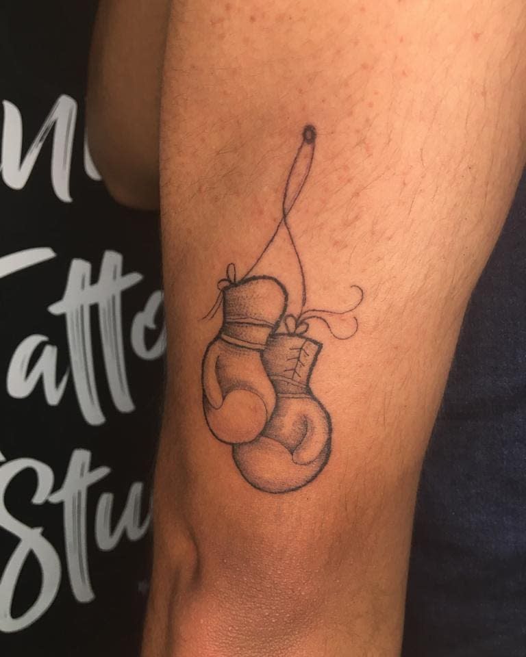 Boxing gloves tattoo tied together, symbolizing strength and resilience