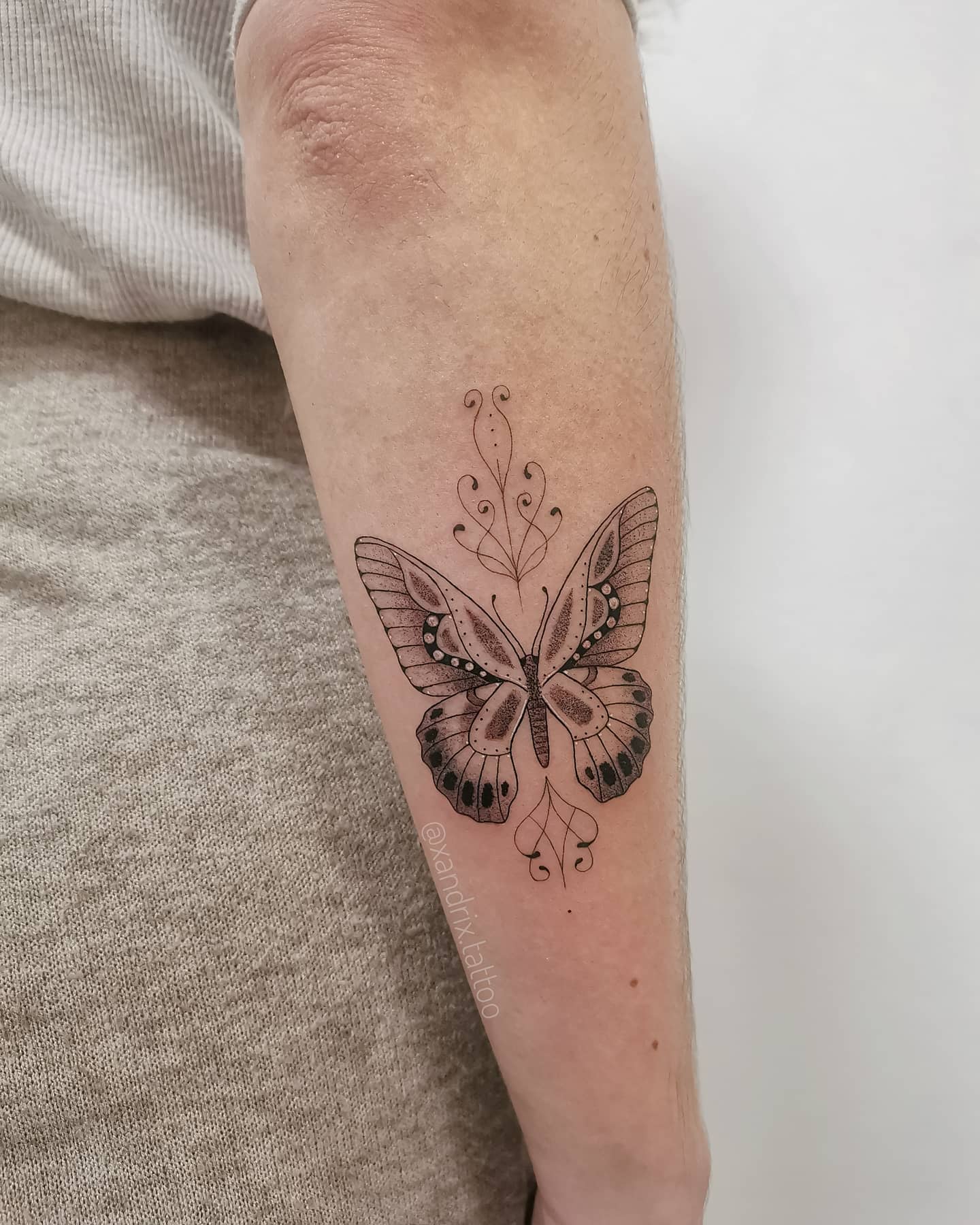 Forearm tattoo of an intricate butterfly with detailed wings and elegant patterns