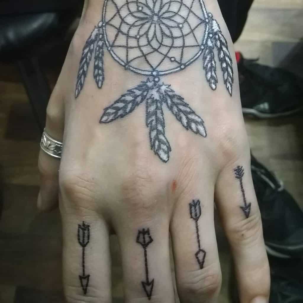 Black and grey tattoo of dreamcatcher and seven hanging feathers, with four arrows