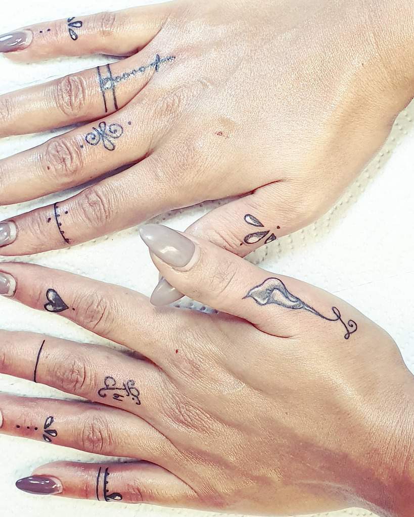 Minimalist finger tattoos featuring delicate linework, hearts, dots, swirls, and ornamental accents