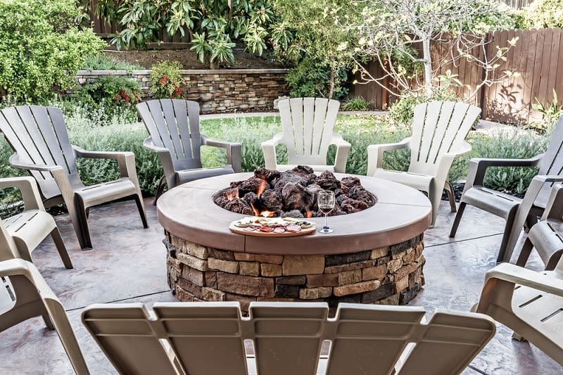 circular stone fire pit with plastic chairs