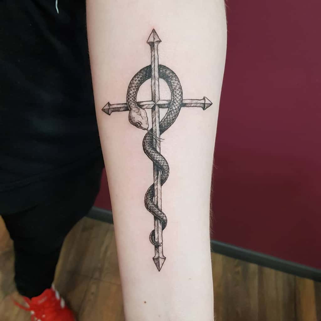 Fullmetal Alchemist tattoo of the Flamel symbol, featuring a detailed black and grey snake wrapped around a cross with arrowed ends