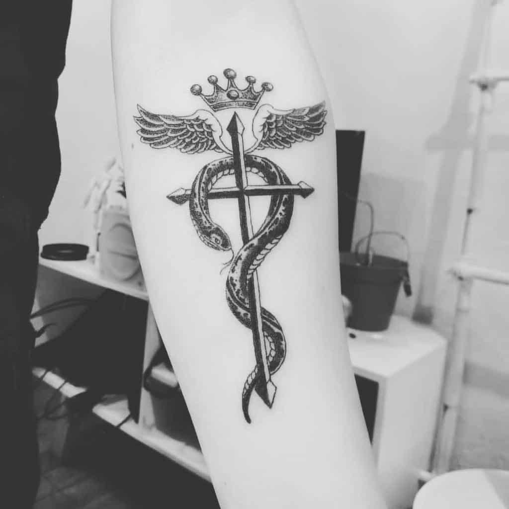 Fullmetal Alchemist tattoo of the Flamel symbol, featuring a detailed snake wrapped around a cross with wings and a crown above