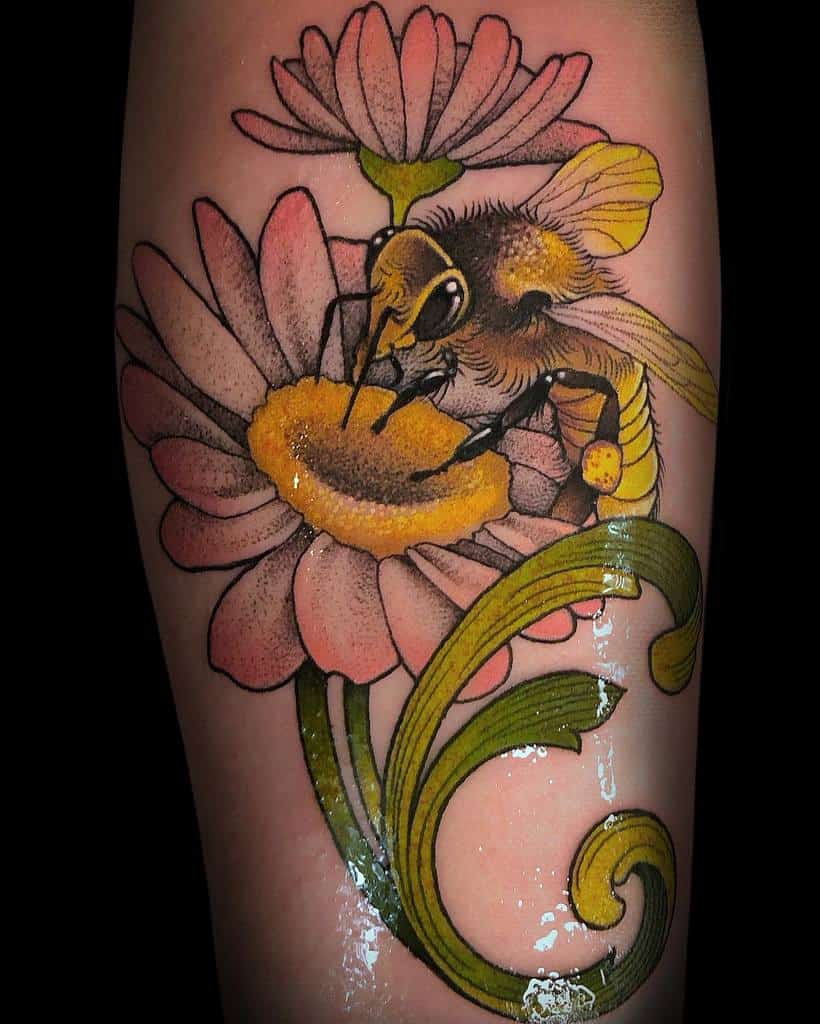 Floral Art Nouveau tattoo of a bee on a daisy, featuring bold outlines, soft shading, and elegant swirling green stems