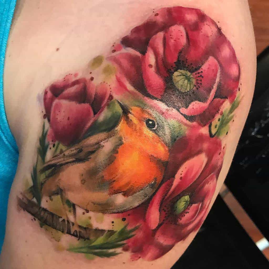 Vibrant watercolor-style tattoo of a robin perched on a branch, surrounded by bold red poppies and soft splashes of green and pink