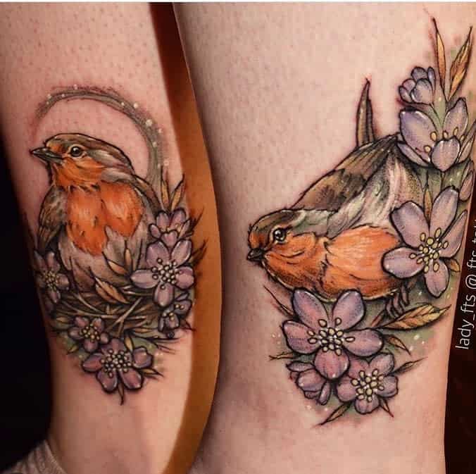 Matching colorful tattoos of robins perched among soft purple flowers and leaves