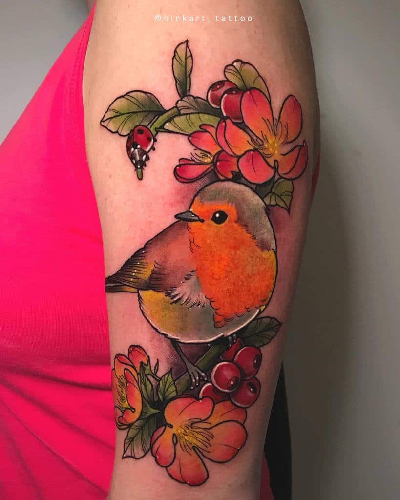 Colorful tattoo of a robin perched on a branch, surrounded by red berries, flowers, green leaves, and a small ladybug