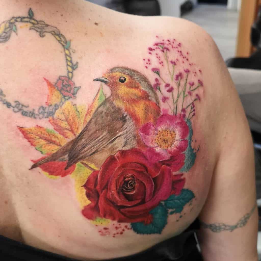 Colorful tattoo of a robin perched among colorful flowers and leaves