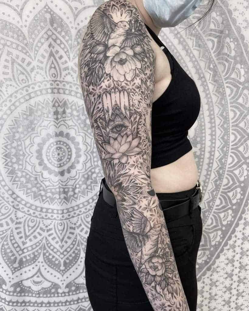 Woman with a detailed black and gray sleeve tattoo of floral and animal designs