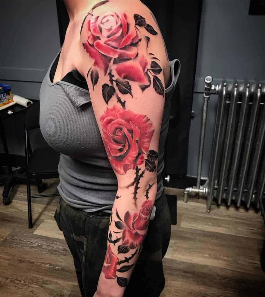 Woman with a colorful rose tattoo sleeve on their arm