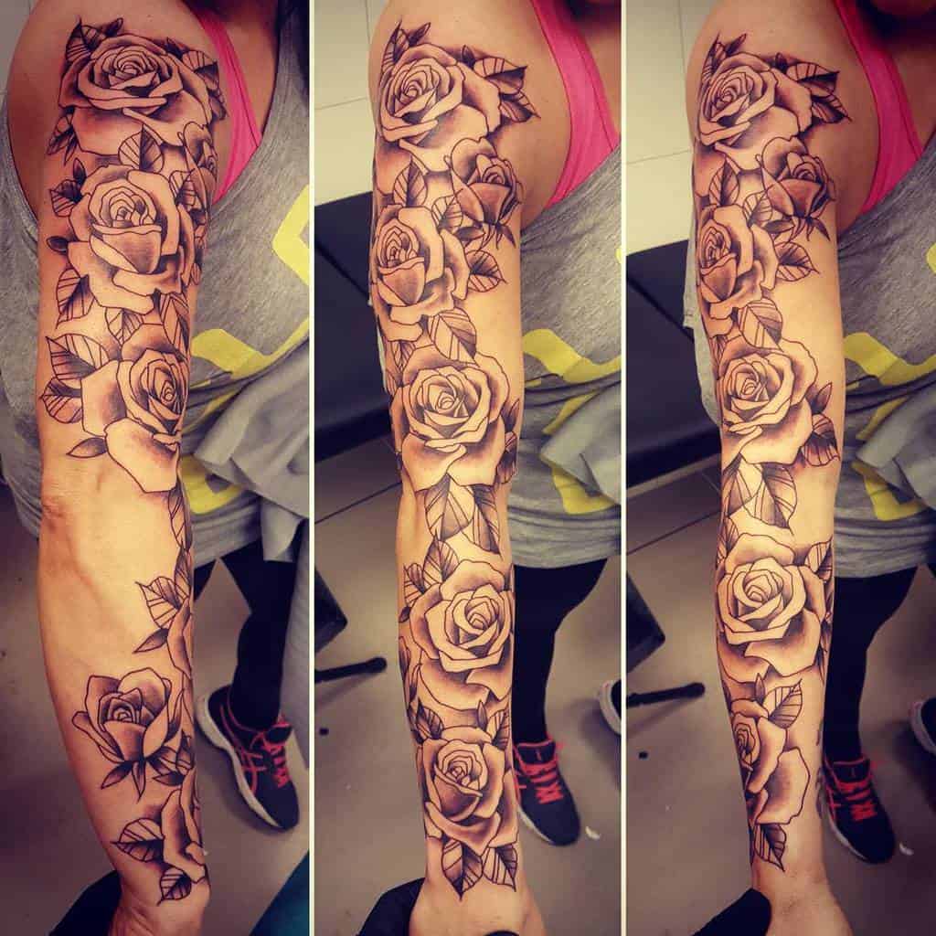 Arm sleeve tattoo with roses and leaves in black and grey ink