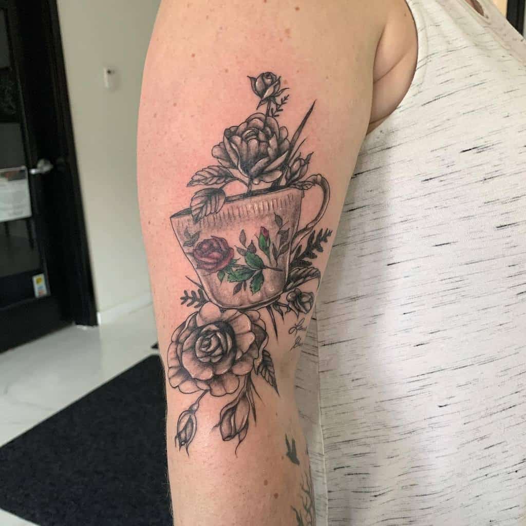 Black and grey tattoo of a vintage teacup with red roses growing from it, featuring intricate shading and delicate floral details