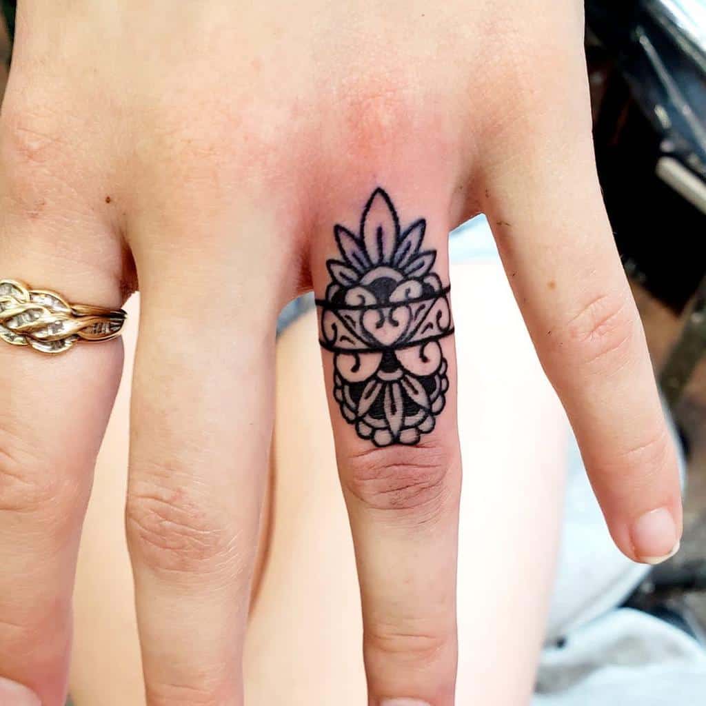 A bold and intricate black line ring tattoo with symmetrical floral patterns, creating an elegant design