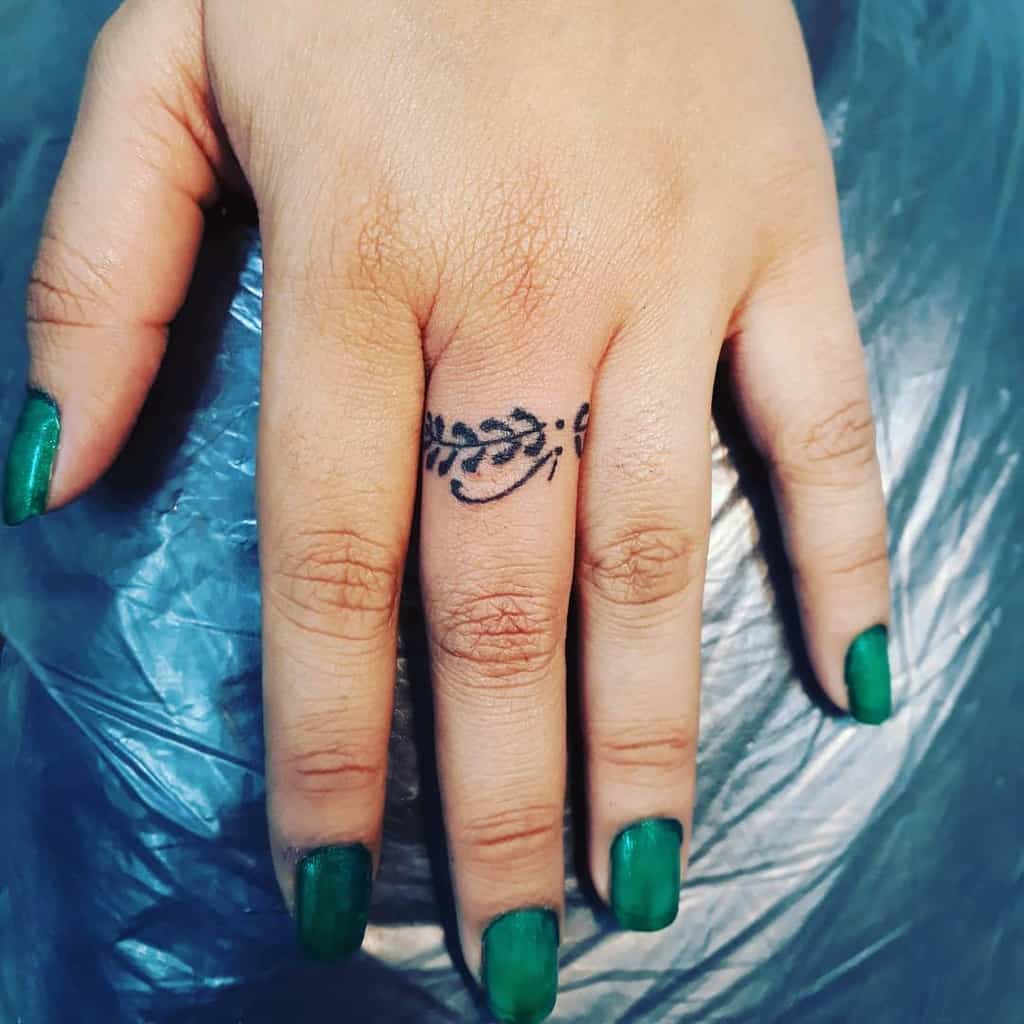 A simple and elegant ring tattoo featuring a delicate vine with leaves
