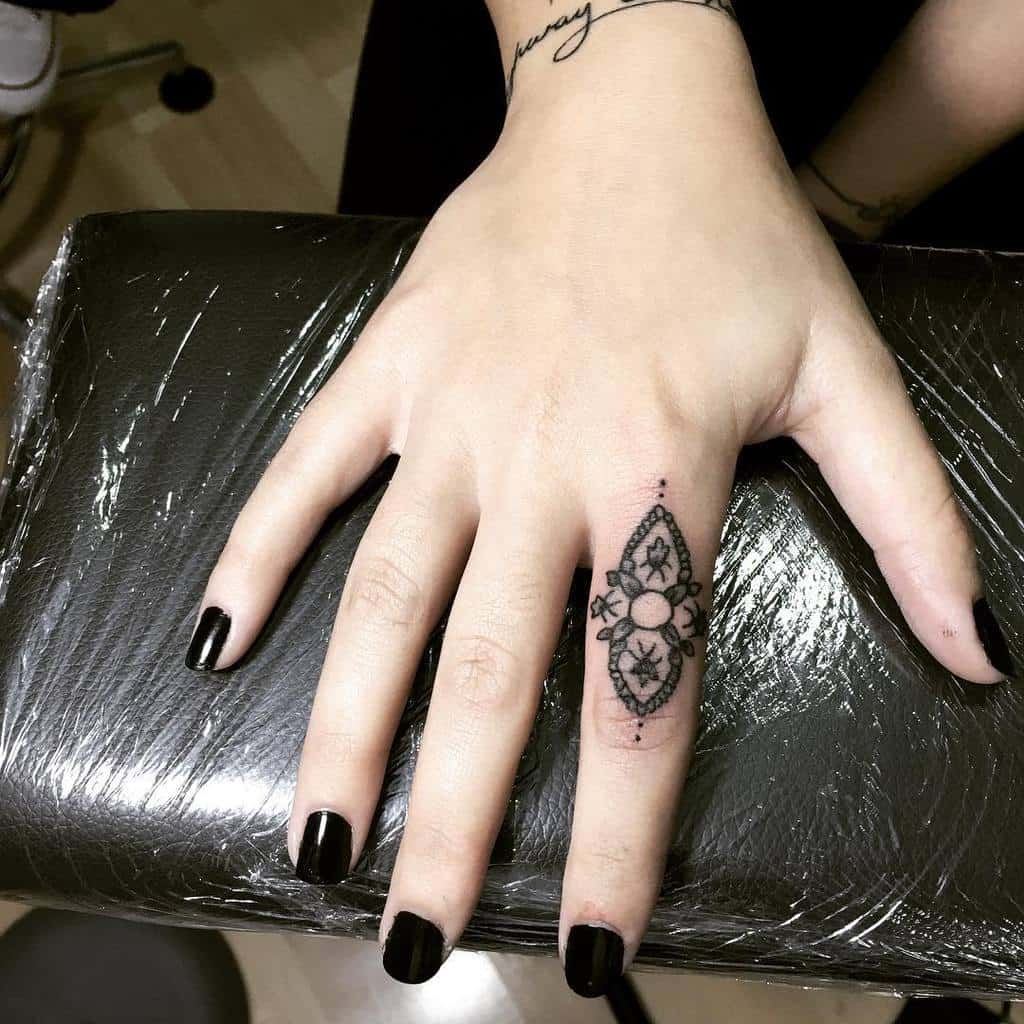 A striking black line ring tattoo with intricate geometric patterns and floral elements