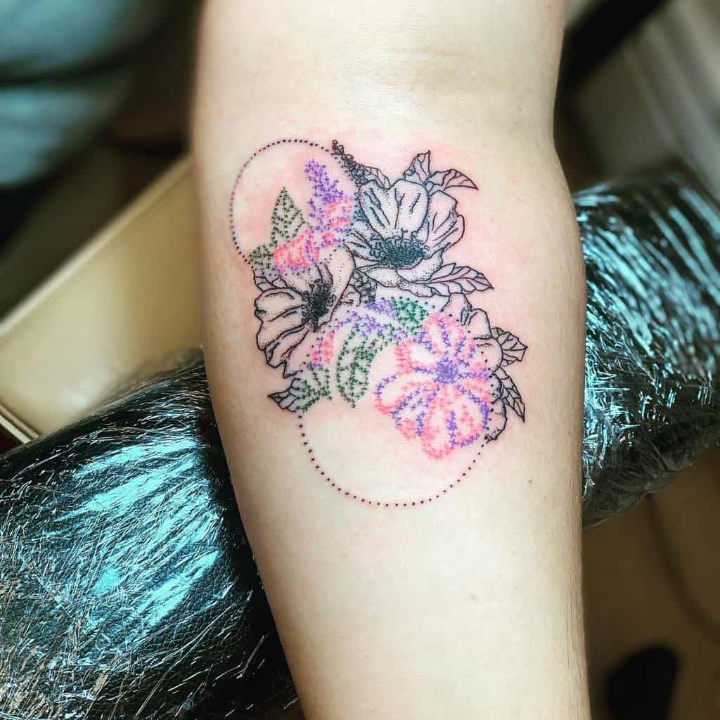 Cross-stitch floral tattoo blending black ink flowers with pastel embroidery-style details with circle dots