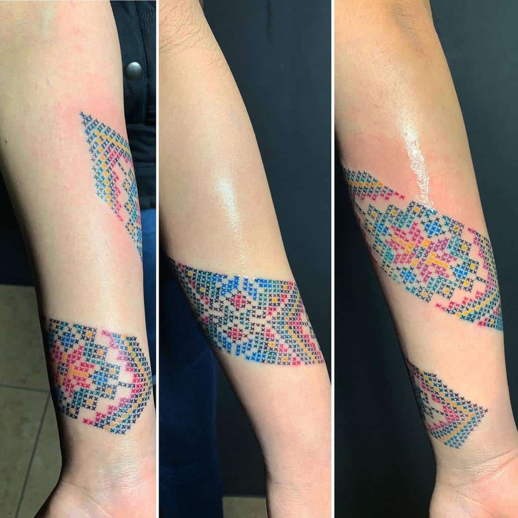 Cross-stitch tattoo armband with intricate geometric patterns in red, blue, and black, resembling traditional embroidery