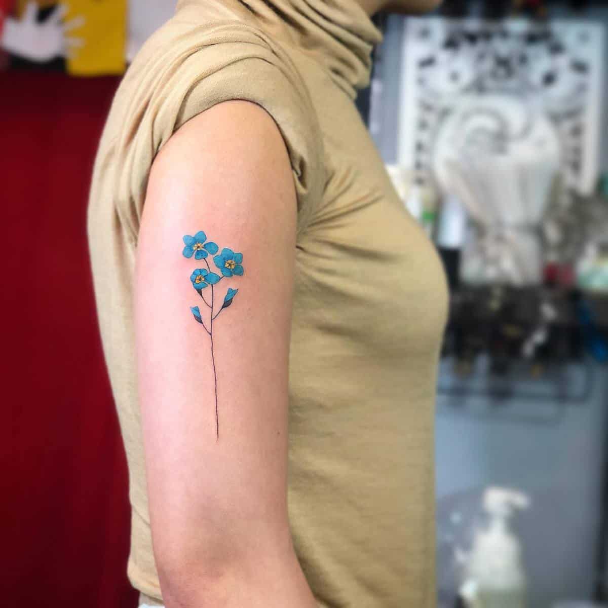 A blue flower tattoo on the upper arm