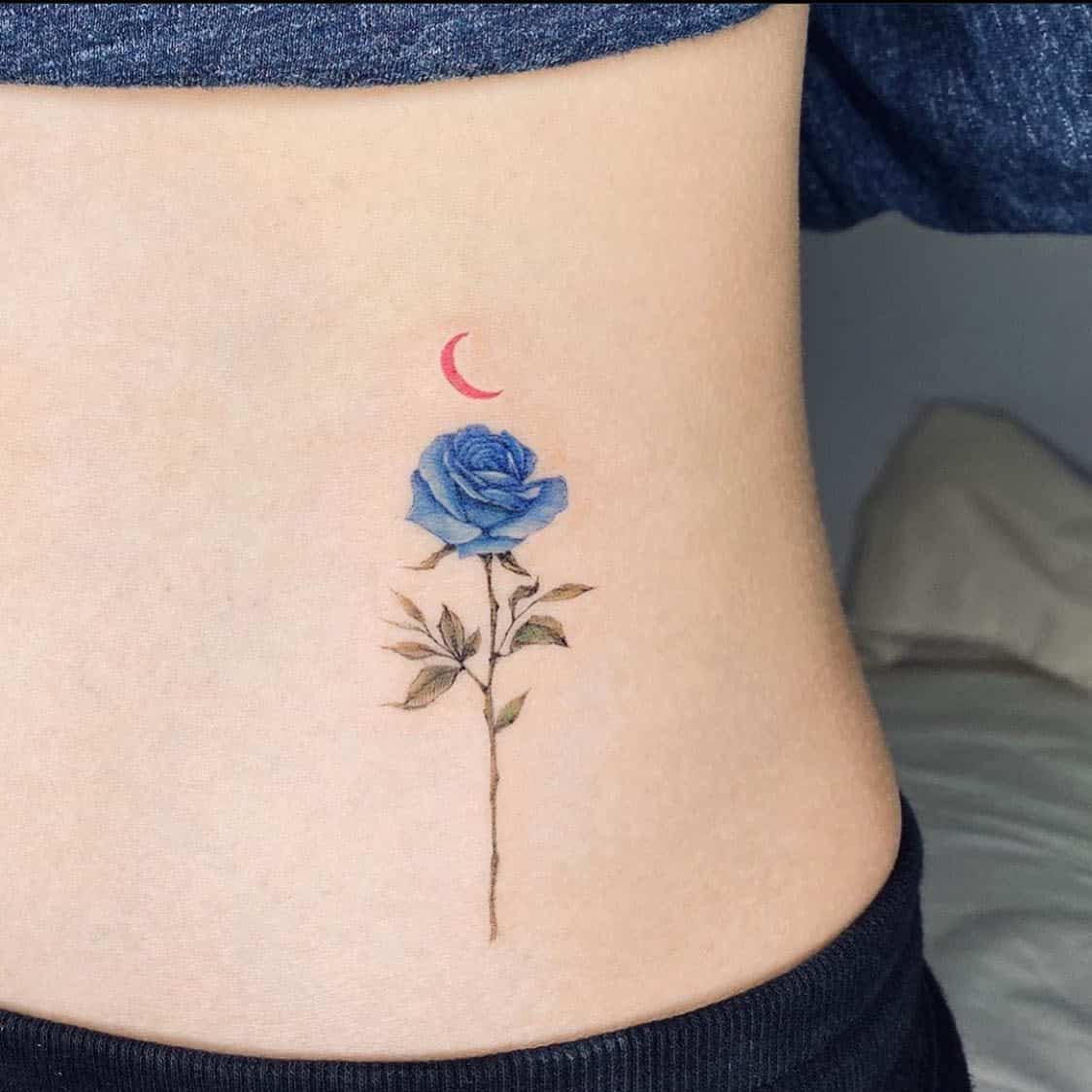 Tattoo of a blue rose and red crescent moon on the side of a torso