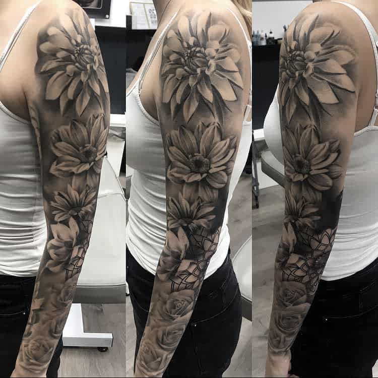 Elegant black and gray sleeve tattoo featuring large blooming flowers with intricate shading and detailed petals