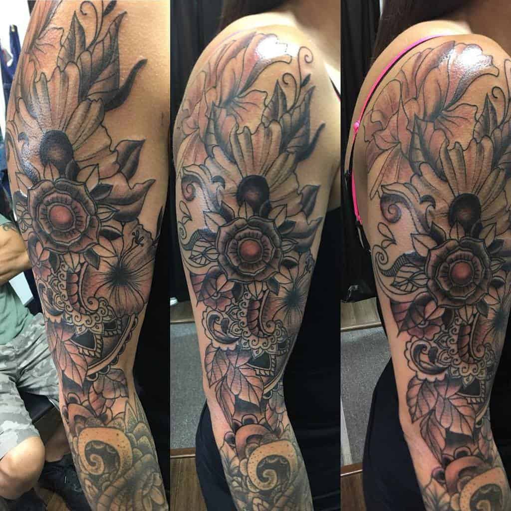 Intricate floral sleeve tattoo with bold outlines, detailed petals, and ornamental patterns, creating a striking and artistic design