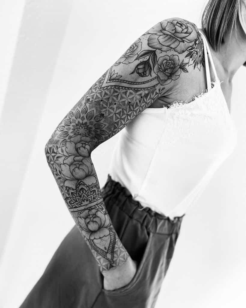 A woman showcases a detailed floral sleeve tattoo on their arm
