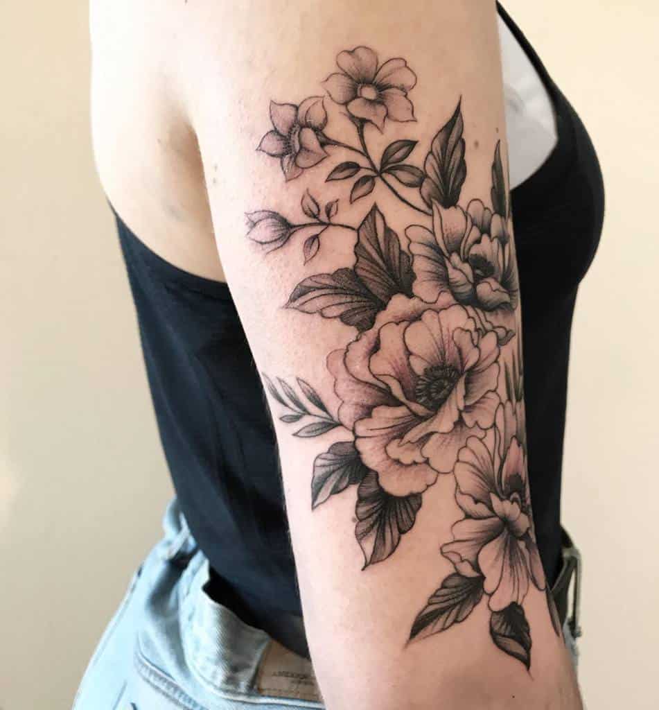 Arm with detailed black and gray floral tattoo design, featuring roses and leaves