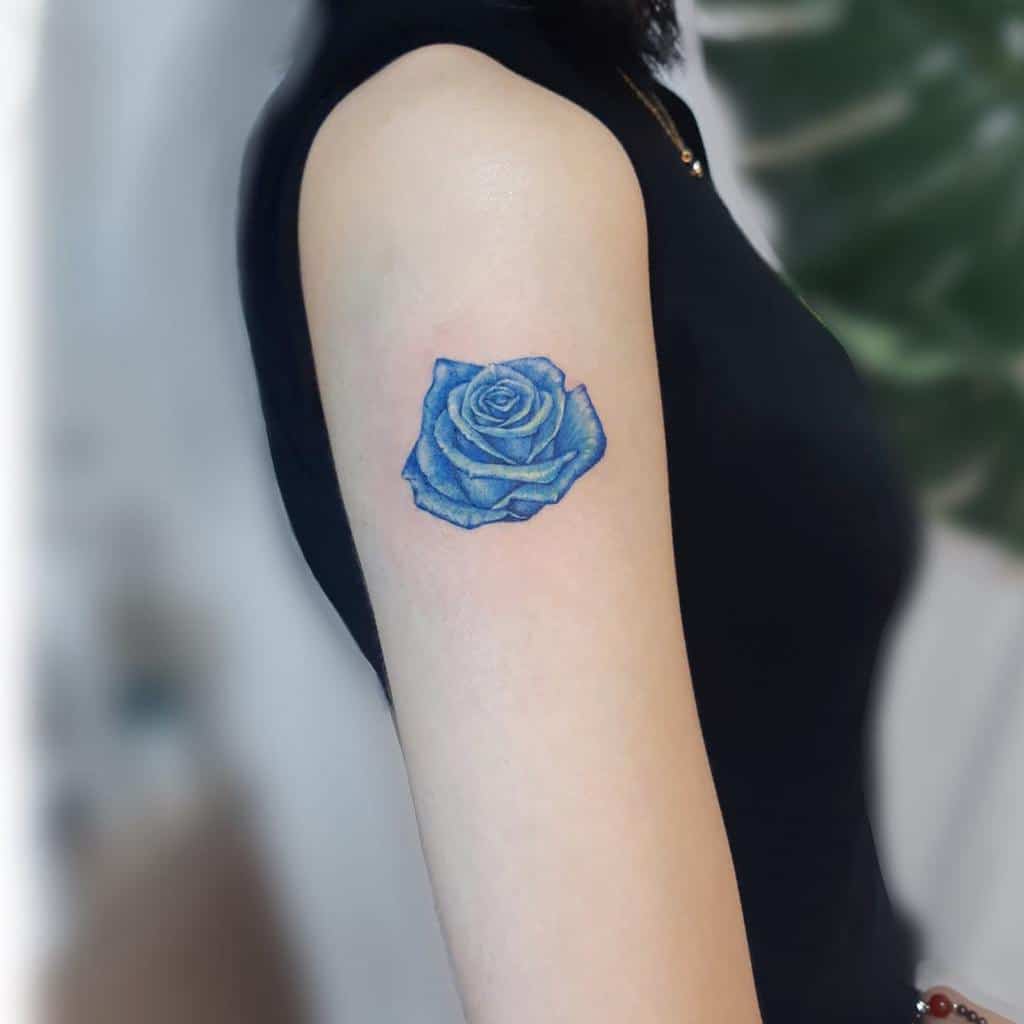A woman with a blue rose tattoo on her upper arm