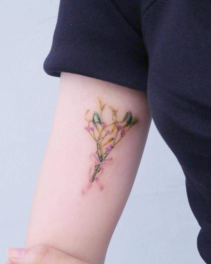 A delicate flower tattoo with leaves wraps around the inner arm