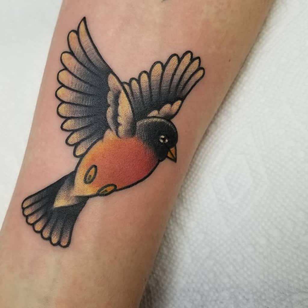 Tattoo of a colorful robin with outstretched wings, the robin has red, black, and yellow hues