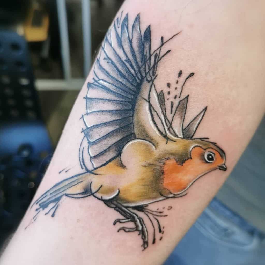 Colorful tattoo of a flying robin with outstretched wings and orange chest