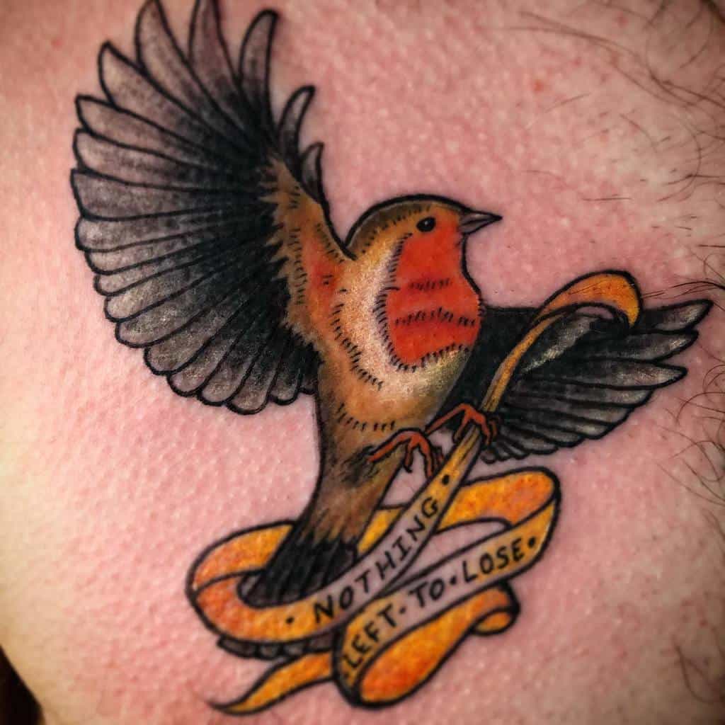 Colorful tattoo of a flying robin with outstretched wings and a yellow ribbon reading "Nothing Left to Lose"