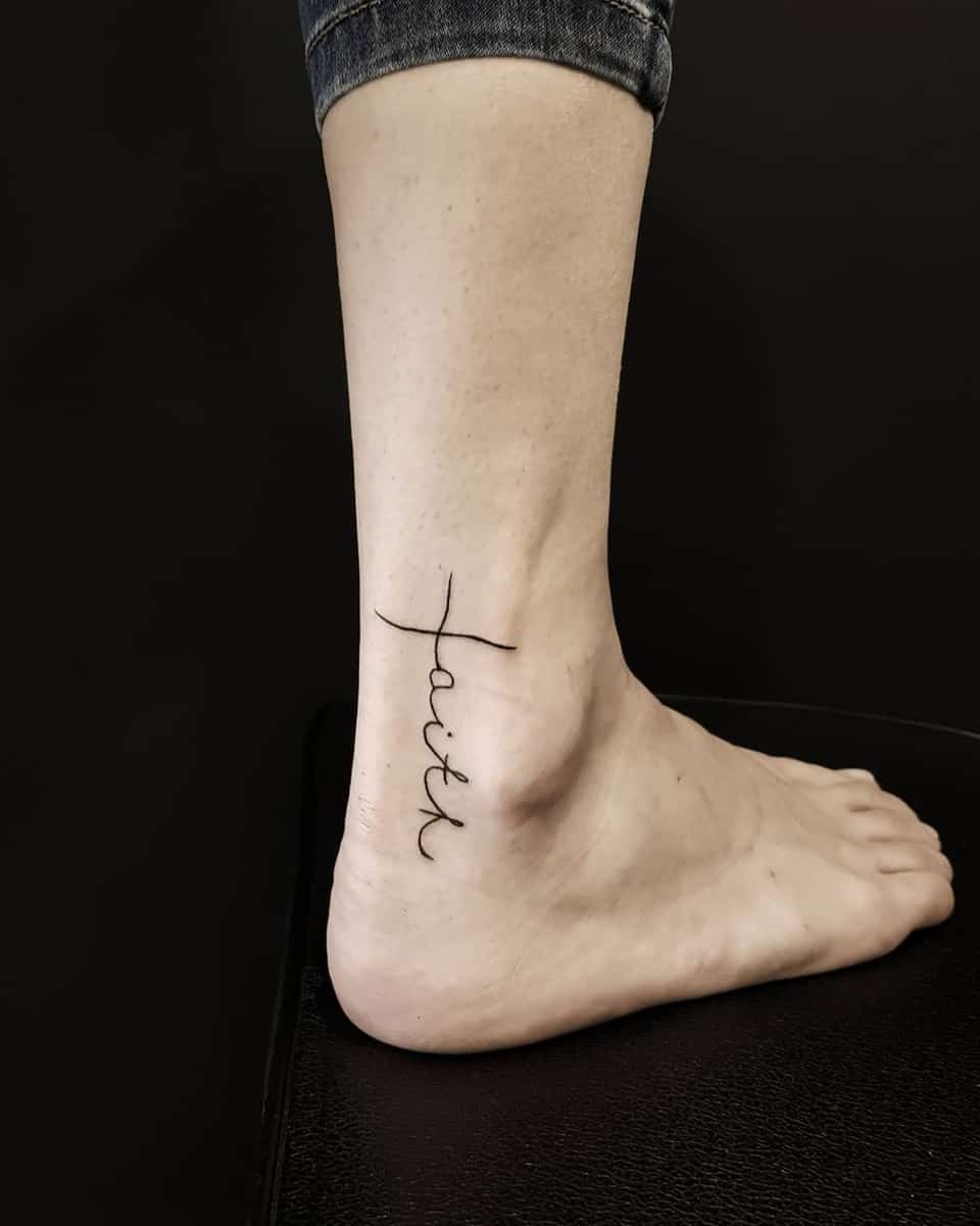 Side view of an ankle with a tattoo of the word "faith" in cursive on the side against a dark background