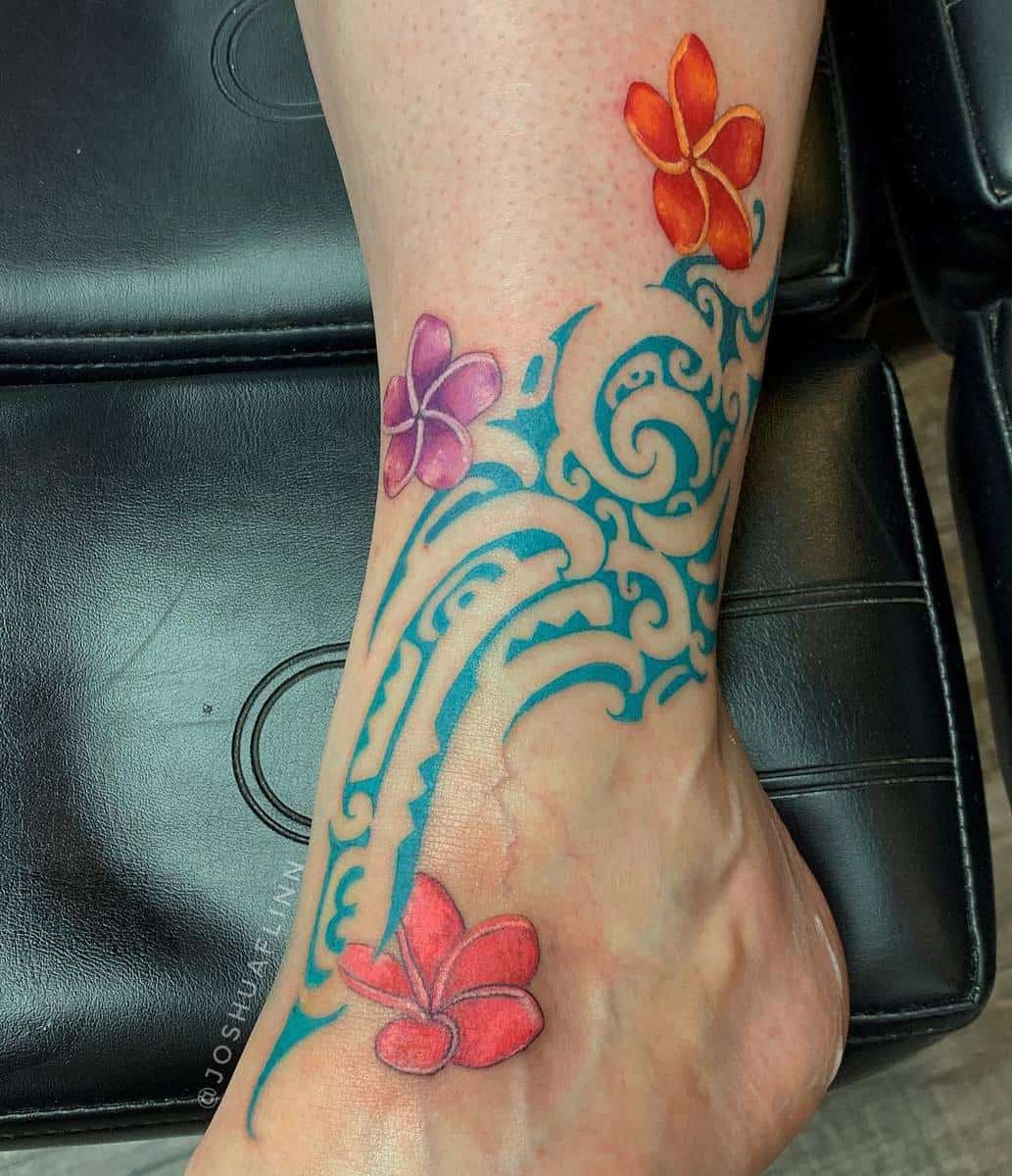 A tattoo on an ankle features intricate blue swirls with red, purple, and orange flowers