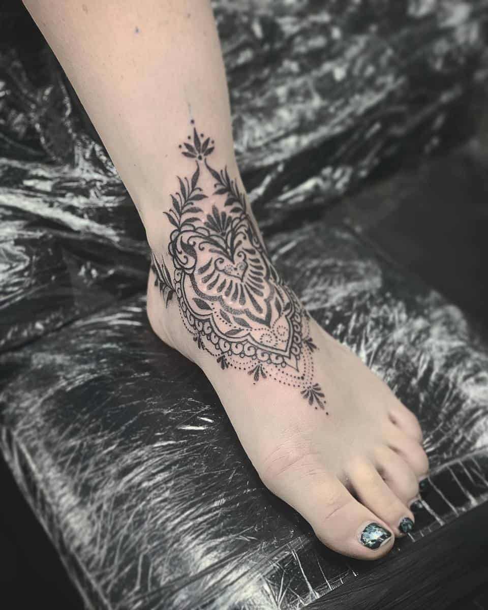 A foot with a mandala black tattoo design covering the top and twisting around the ankle